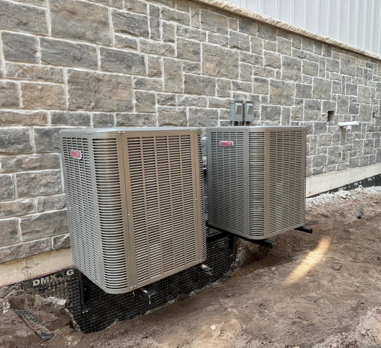 Dual Lennox air conditioning units installed on wall-mounted brackets to save space and protect from ground debris.