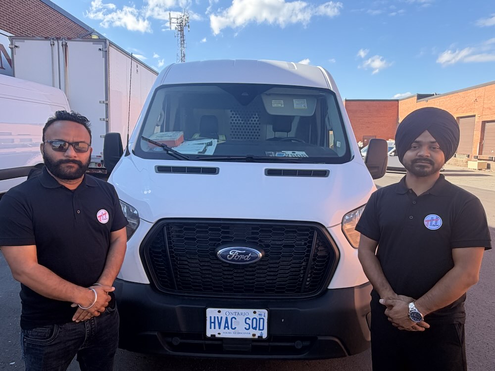 Two The HVAC Squad technicians standing beside a branded service van