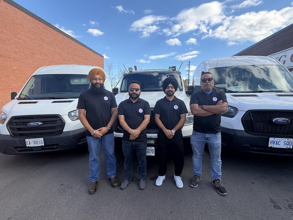 The HVAC Squad team standing in front of three company service vehicles