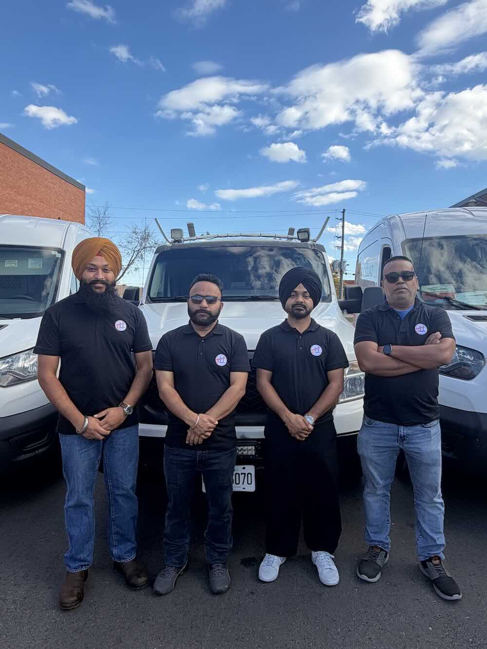 Four The HVAC Squad team members standing in front of company service vans